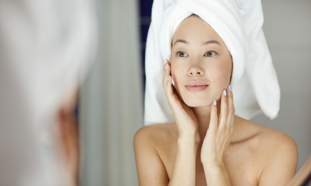 woman with perfect skin looking in mirror