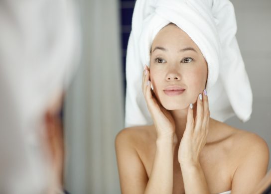 woman with perfect skin looking in mirror