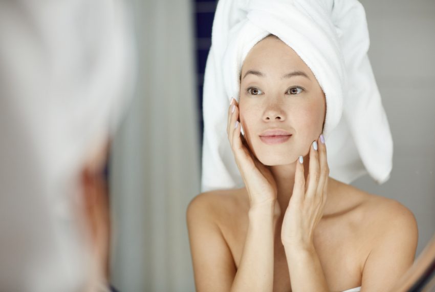 woman with perfect skin looking in mirror