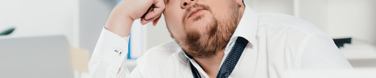 Image of a thoughtful fat businessman with laptop at workplace in office