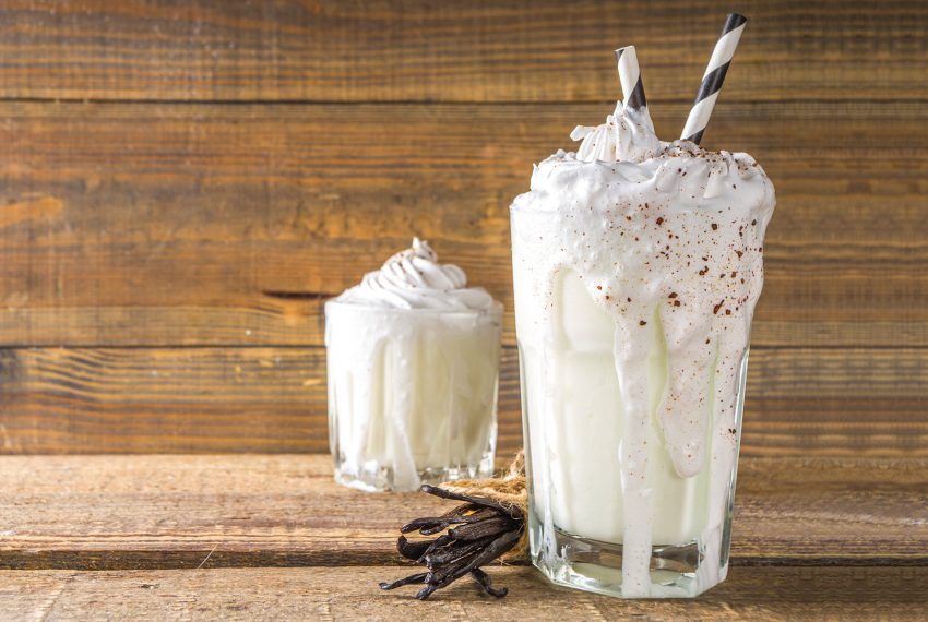 National Milkshake Day. A photo of two vanilla milkshakes / beverages with whipped cream on top.