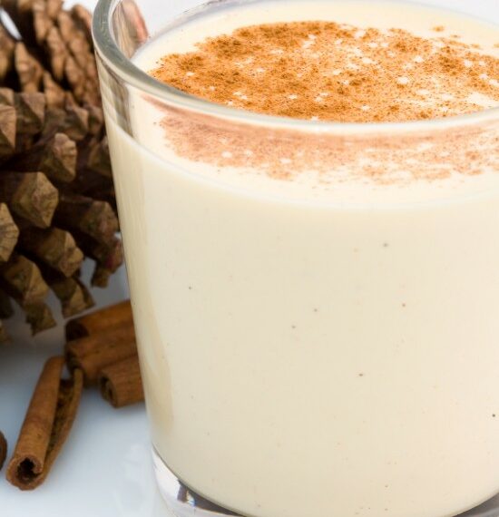 eggnog in a glass with cinnamon sticks